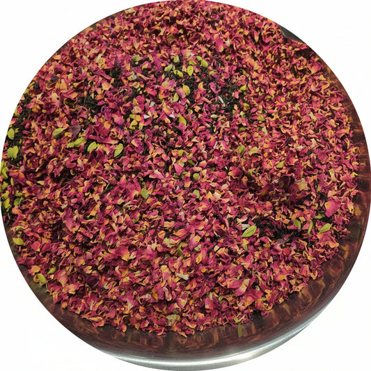Metal strainer filled with pink and green flower petals on a wooden surface